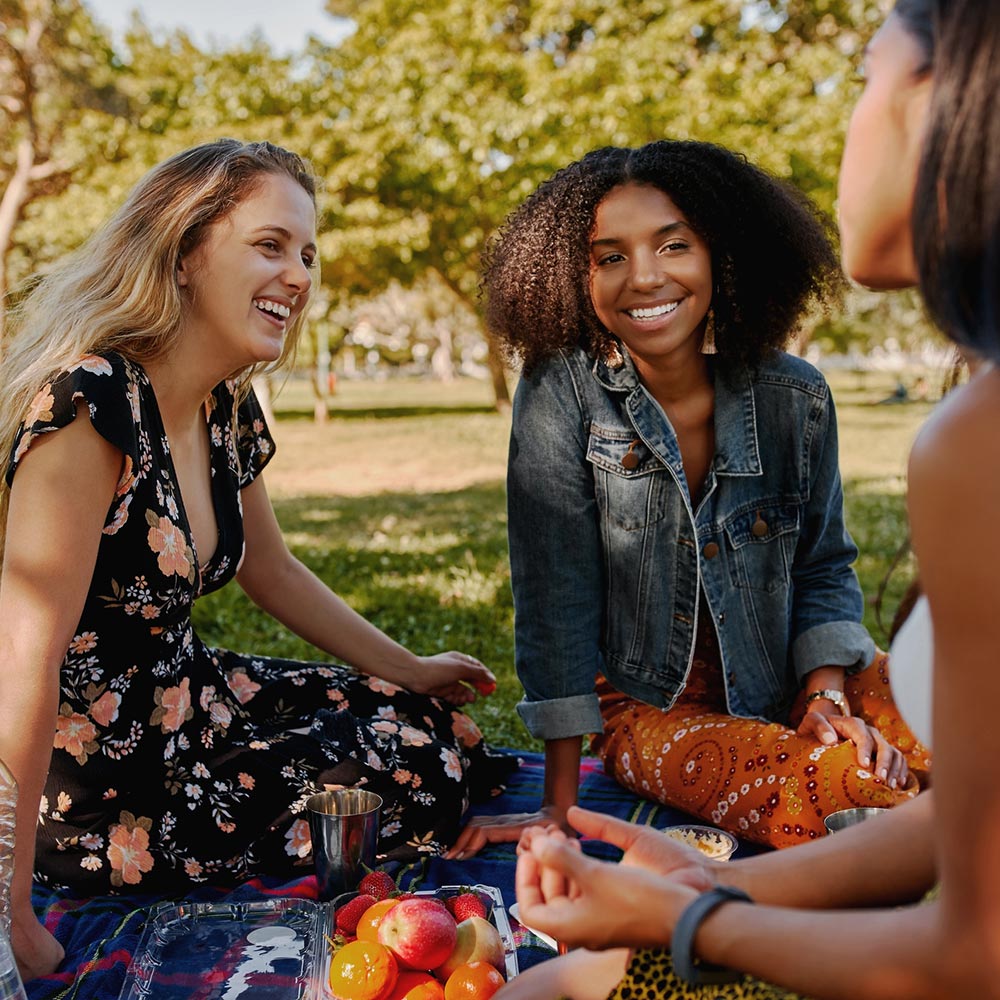 Smiling multiracial female friends having fun at picnic in the park